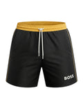 picknpack BOSS black swim shorts with a mustard yellow elasticated waistband, drawstring, and logo detail.