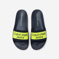 picknpack Calvin Klein Jeans navy blue pool slides with a vibrant neon yellow strap and bold logo branding.