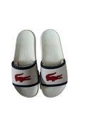 picknpack Lacoste white slip-on sandals with a red crocodile logo on the strap and a contoured footbed.
